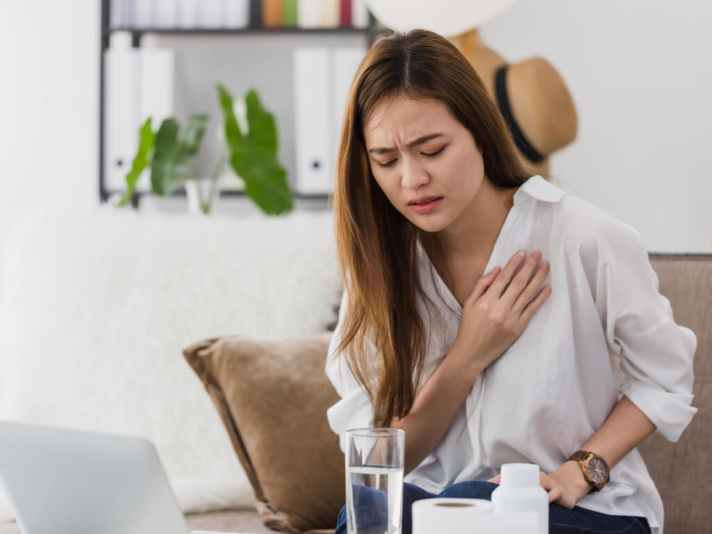 A woman struggling with GERD symptoms. Avoiding certain foods with GERD will help you reduce your symptoms.
