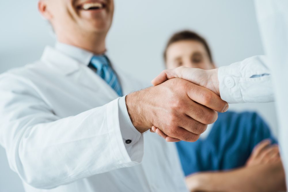 A patient shaking hands with a general surgeon and a surgeon's assistant at a general surgery office in Nashville, TN