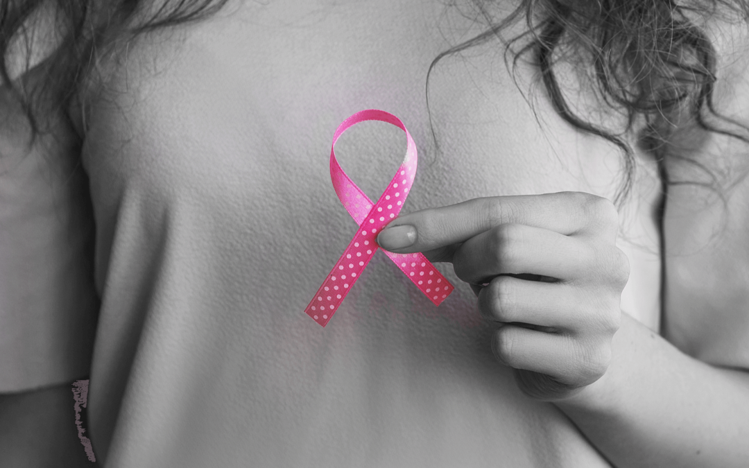 Woman holding a pink ribbon to represent breast cancer awareness month.