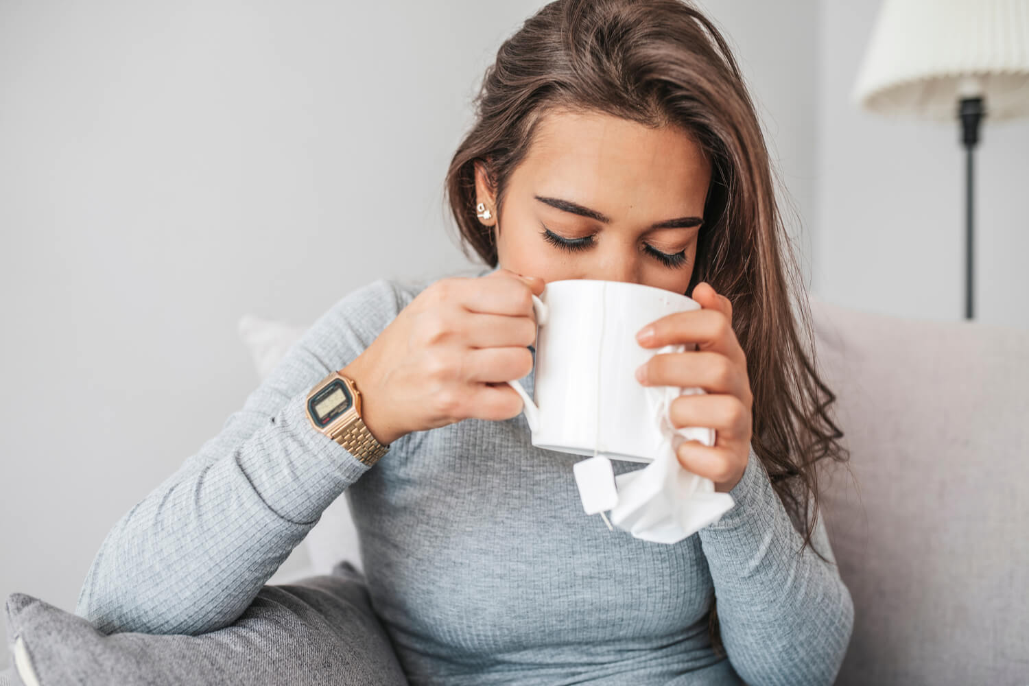 Woman drinking tea on the couch in the winter as she recovers from vascular surgery
