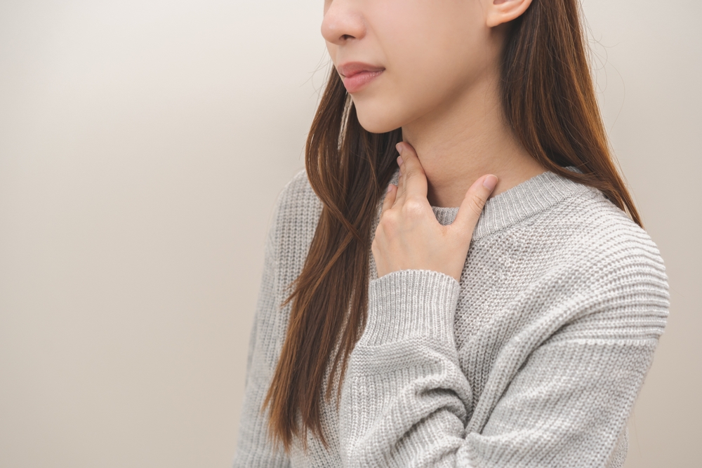 Sickness,In,Inflaming,Asian,Young,Woman,,Girl,Use,Hand,Check A woman touching her neck to check her thyroid.