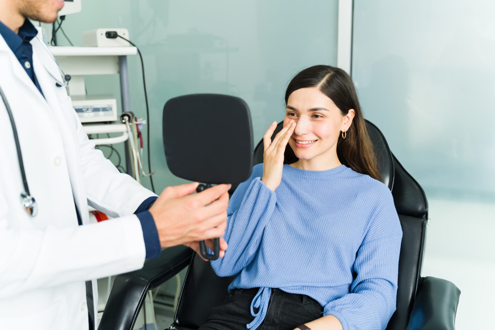 Patient looking into mirror at face with doctor nearby.