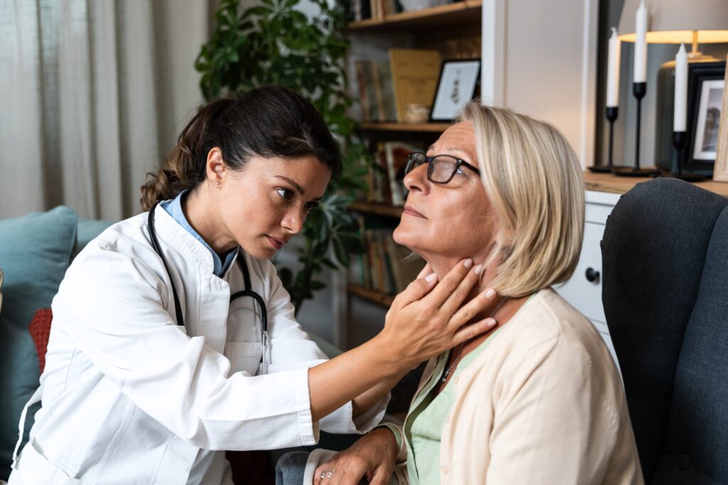 Doctor checking woman's thyroid.