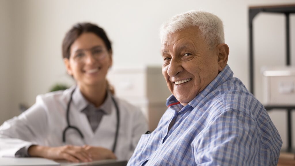 Older male patient with doctor, smiling, hopeful. 