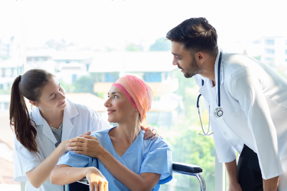 Two doctors smiling at a patient with cancer.